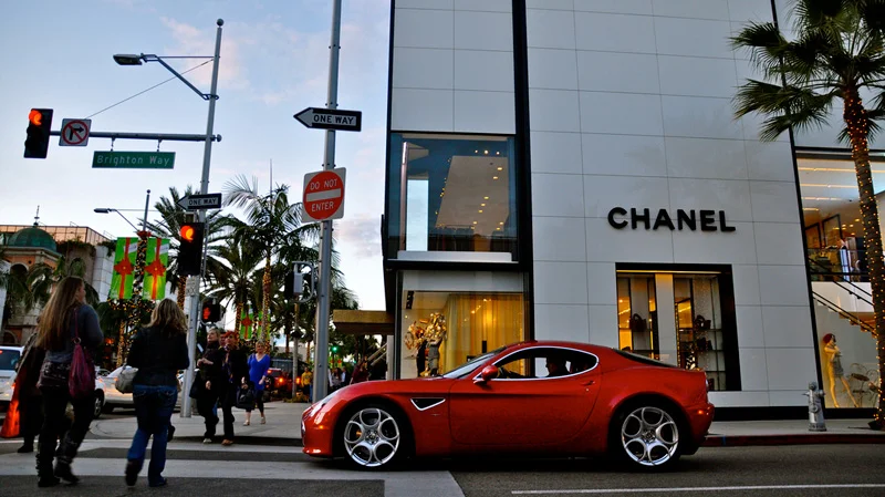 une voiture de sport rouge est garée devant un magasin chanel.